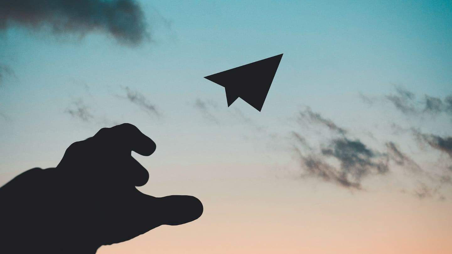 Image of a hand throwing a paper plain into a dawn sky