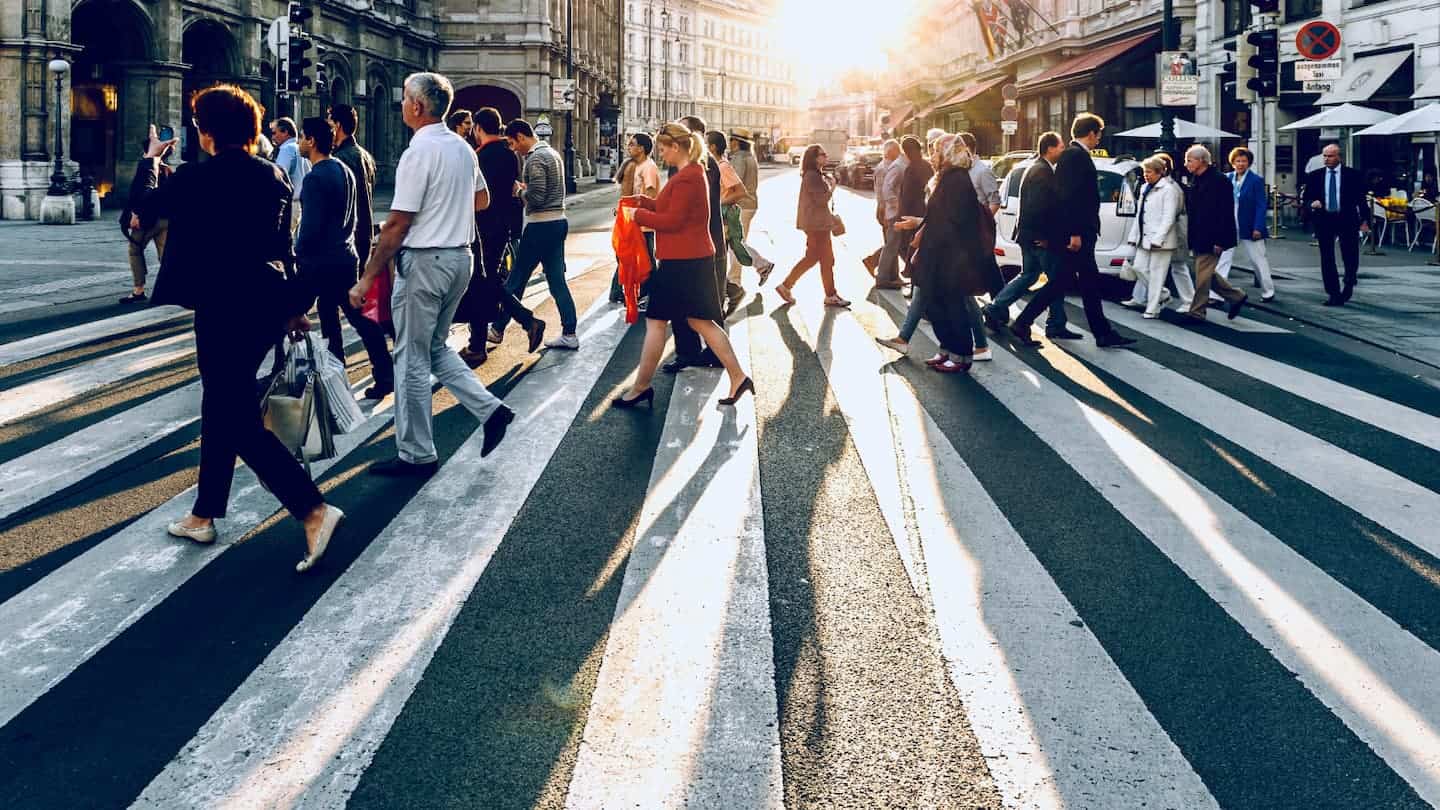 An image of people walking across a road crossing in a major US city