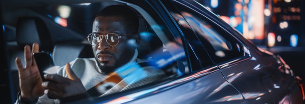 Image of a man in a limousine checking his bank balance on his phone