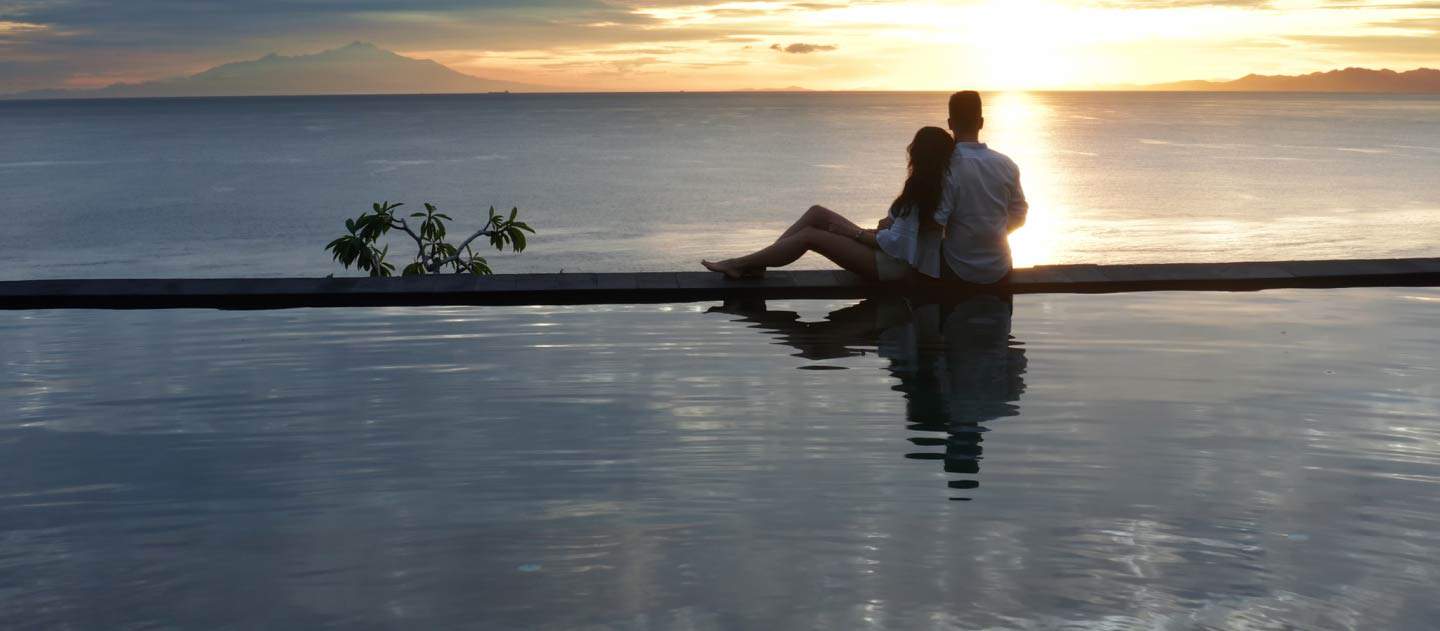 Image of a couple watching the sunset over the ocean from the edge of an infinity pool