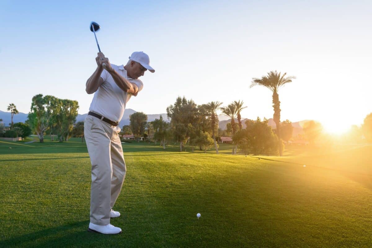Man playing golf as the sun rises in the background