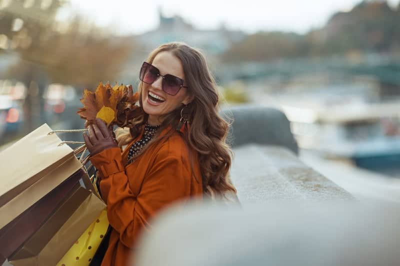 Image of a stylish young woman smiling and holding shopping bags